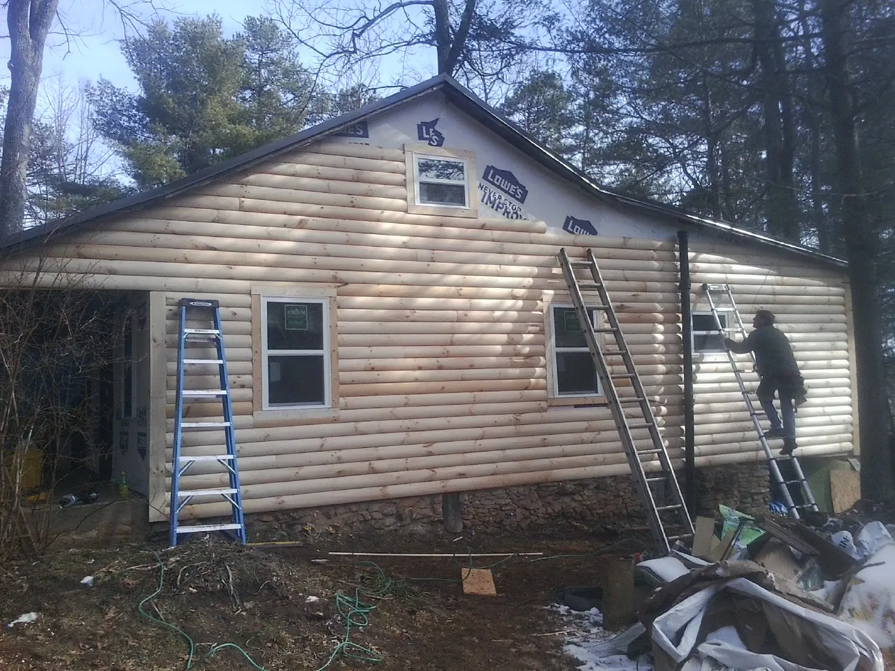 Ladders set against fresh log siding during an exterior remodel in Thayer