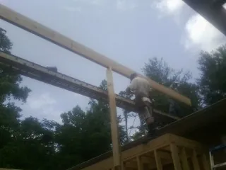 Carpenter setting a ridge beam over a new addition frame — Ice Dam Removal by Roofing Brothers in Thayer